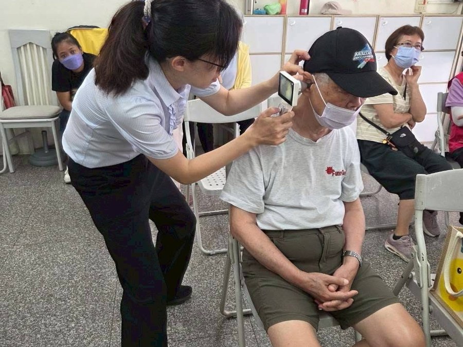 上聆人員在社區據點為一位長者做聽力檢查，旁邊還有其他等候的長輩